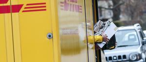 Ein DHL-Paketzusteller verlässt mit mehreren Sendungen sein Fahrzeug im Paulusviertel in Halle.