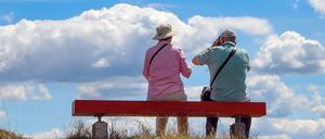 Zwei ältere Personen sitzen auf einer Bank, die auf einem Hügel im Nationalpark Unteres Odertal steht. 
