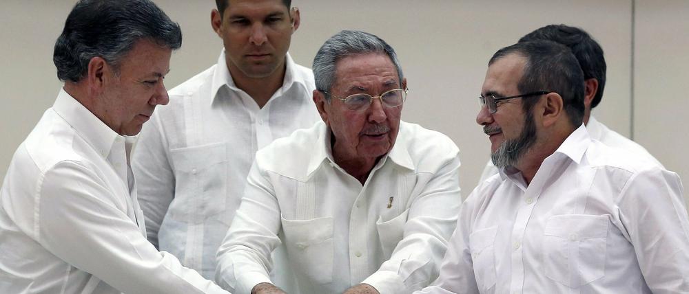 Aussicht auf Frieden in Kolumbien: Präsident Juan Manuel Santos (links) und Rebellenführer "Timochenko" (rechts) besiegeln die Einigung, in der Mitte Kubas Präsident Raul Castro. 
