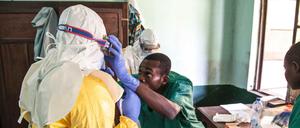 Mitarbeiter des Gesundheitswesens ziehen in einem Behandlungszentrum in Bikoro Schutzausrüstungen gegen Viren an. 