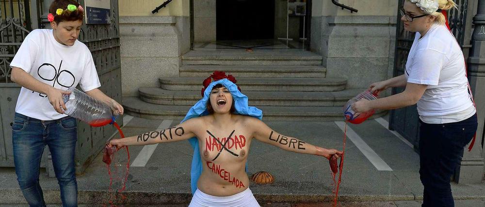 Mit nackten Brüsten kniet am 23. Dezember eine Aktivistin der Frauenrechtsgruppe Femen vor einer Kirche in der Hauptstadt Madrid. Auf Oberkörper und Arme hatte sie die Slogans „Weihnachten ist abgesagt“ und „Freie Abtreibung“ geschrieben.