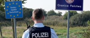 Bei einer flexiblen Schwerpunktkontrolle an der deutsch-polnischen Grenze steht ein Bundespolizist vor den Schildern für Deutschland und Polen. 