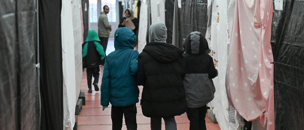 Flüchtlingskinder gehen durch ein Zelt einer Flüchtlingsunterkunft (Symbolbild).