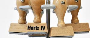 Ein Stempel mit der Aufschrift Hartz IV hängt an einem Stempelträger.