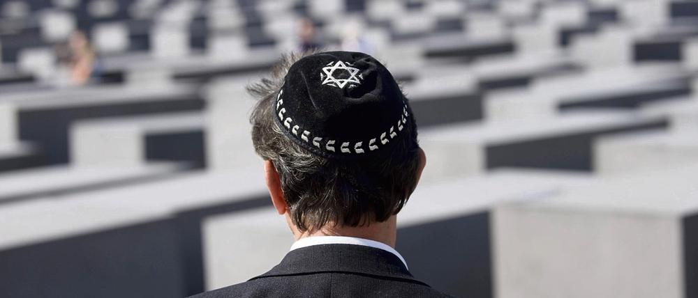 Eine Jude mit der traditionellen Kopfbedeckung Kippa und einem Davidstern auf dem Gelände des Holocaust Mahnmals in Berlin.