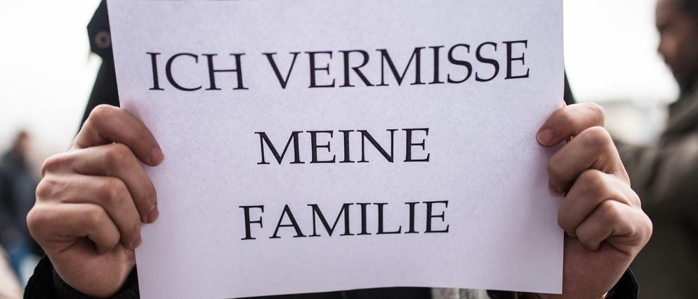 Ein Mitglied des Flüchtlingsrats Berlin weist mit einem Schild auf die emotionale Bedeutung des Familiennachzugs hin.