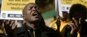 Ein Mann singt vor Plakaten mit dem Text "Get well soon Madiba"