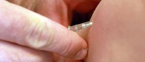 Ein Kinderarzt gibt einem Mädchen eine Masernimpfung. 