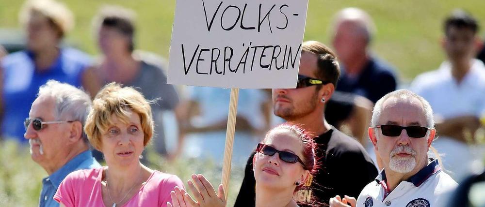 Viele waren es Reportern zufolge nicht - aber einige Anwohner buhten Bundeskanzlerin Angela Merkel bei ihrem Besuch in Heidenau aus. Auf einem Plakat wurde die Kanzlerin als "Volksverräterin" bezeichnet.