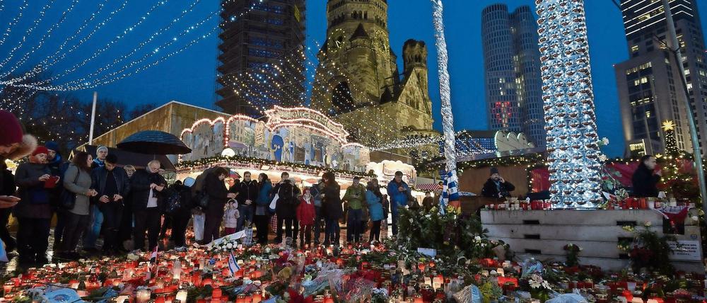 Zahlreiche Menschen stehen am 22.12.2016 um die Blumen und Kerzen, die am Weihnachtsmarkt am Breitscheidplatz in Berlin abgelegt wurden. 