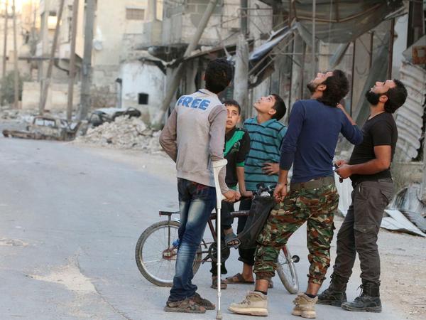 Auf der Straße beobachten Bewohner von Aleppo die Luftangriffe.