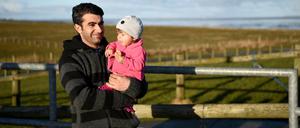 Der Syrer Ahmed Alsamiye steht auf der Hallig Langeneß (Schleswig-Holstein) mit seiner einjährigen Tochter Halasham auf der Warft. Die Flüchtlingsfamilie aus Syrien hat auf der Hallig Langeneß ihr neues Zuhause gefunden.