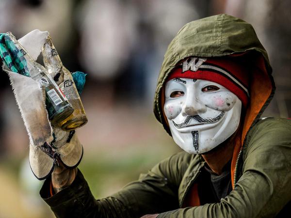 Ein maskierter Demonstrant in Caracas mit Molotowcocktails in der Hand. 