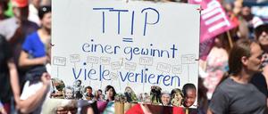 Demonstranten halten am 04.06.2015 in München (Bayern) bei einer Demonstration gegen den G7-Gipfel ein Schild mit dem Schriftzug "TTIP - einer gewinnt - viele verlieren". 