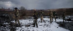 Soldaten gehen auf einer zerstörten Brücke in Irpin.