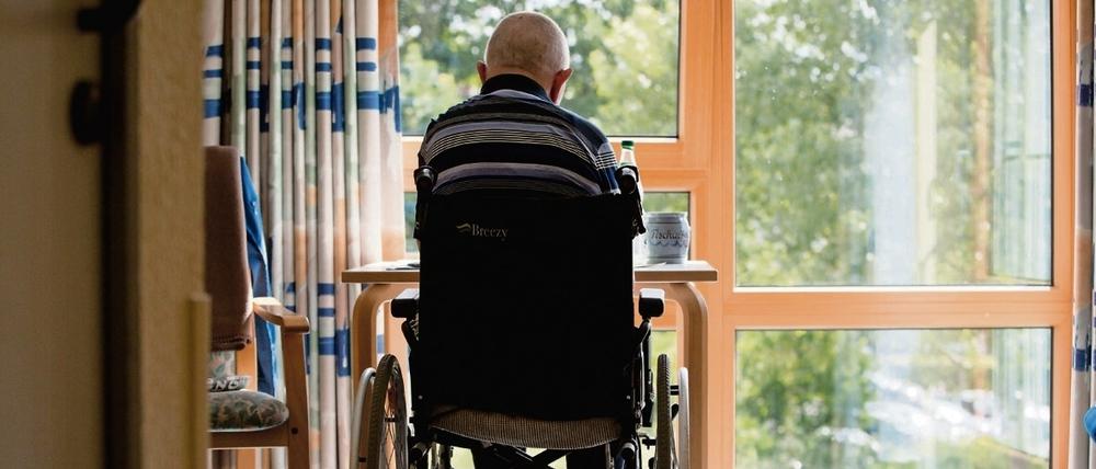 Ein an den Rollstuhl gebundener Bewohner sitzt in einem Altenpflegeheim in seinem Zimmer. 