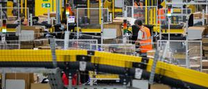 Mönchengladbach: Mitarbeiter mit Mund-Nasen-Bedeckung packen Pakete in einem Logistikzentrum des Versandhändlers Amazon.
