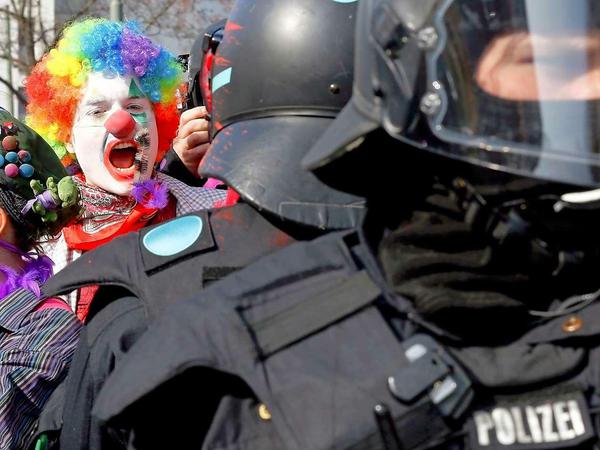 Ein als Clown kostümierter Demonstrant und Polizisten in Frankfurt.