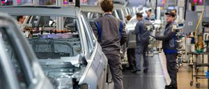 Auf Abstand: Mitarbeiter bauen im Karosseriebau im VW Werk Türen, Kotflügel und Motorhauben an Volkswagen an.