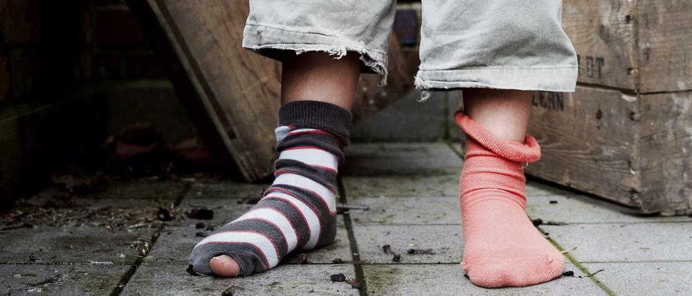 Ein zehn Jahre altes Mädchen steht in abgetragener Kleidung ohne Schuhe in einem Hinterhof in Hamburg.