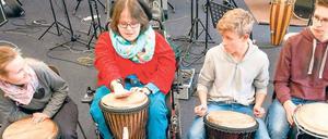 Vier Schüler, eine davon mit einer Behinderung, spielen auf Trommeln.
