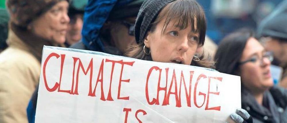 Eine Frau hält ein Schild mit der Aufschrift Climate Change is real in den Händen.