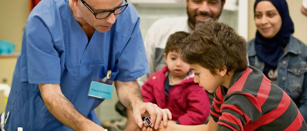 Impfen schützt. Das Foto zeigt einen syrischen Flüchtlingsjungen, der nach der Prozedur gemeinsam mit einem Arzthelfer seinen Impfausweis stempelt. 