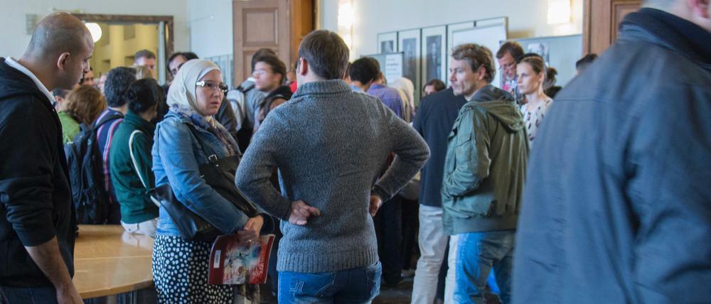 Studierende stehen im Foyer einer Universität und unterhalten sich miteinander.