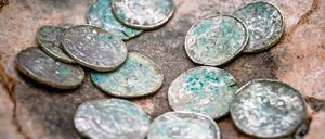 Auf dem Boden eines Tongefäßes liegen antike Münzen.