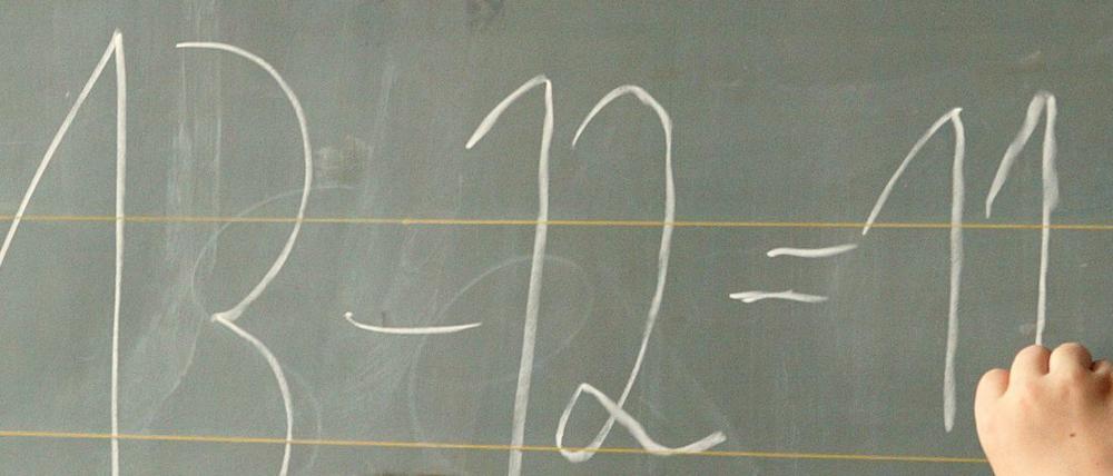 Ein Junge schreibt eine einfache Gleichung an die Tafel.