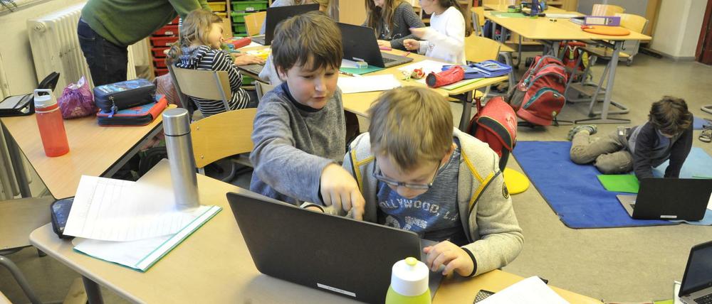 Grundschüler arbeiten im Klassenraum an Laptops.