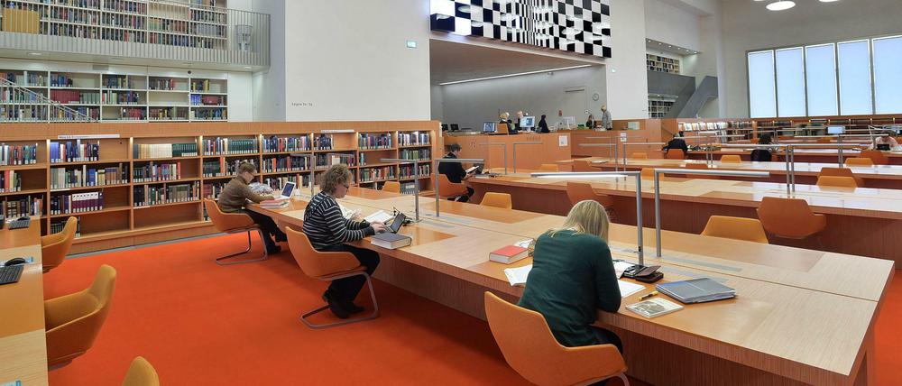 Menschen sitzen in einer Bibliothek an Arbeitstischen.