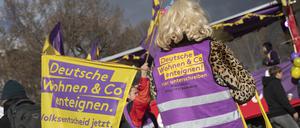 Mit einer Fahne und einer Weste des Bündnisses «Deutsche Wohnen und Co enteignen» steht ein Teilnehmer an der Demonstration «Karneval der Enteignung» in Kreuzberg auf dem Oranienplatz. 