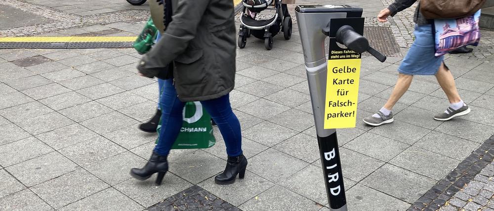 Rücksichtslos auf dem Gehweg abgestellter E-Roller mit "Gelber Karte" des Allgemeinen Blinden- und Sehbehindertenvereins Berlin (ABSV).