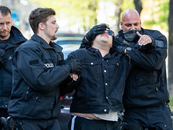 Ein Mann wird am Rande einer Demonstration am Rosa-Luxemburg-Platz abgeführt.