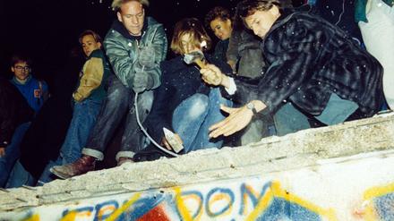 West-Berliner versuchen im November 1989 mit Hämmern und Kreuzhacken die Berliner Mauer einzureißen.