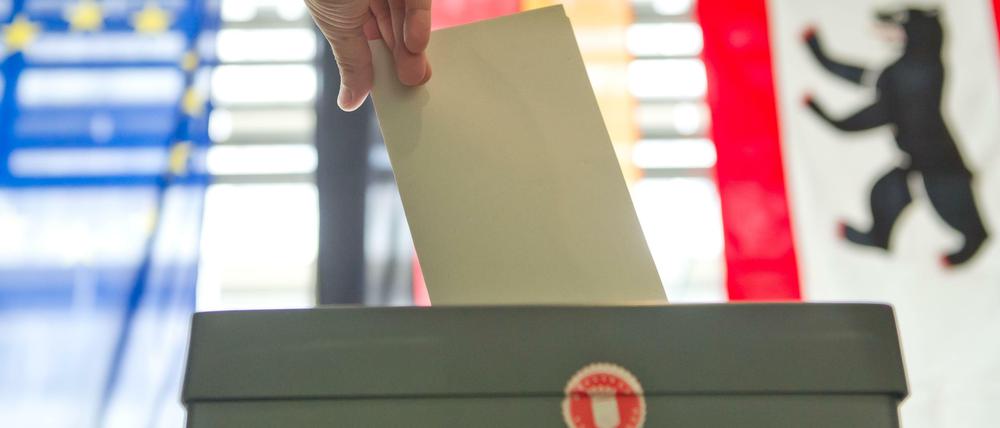 Eine Hand wirft in Berlin bei der Stimmabgabe zur Bundestagswahl einen Stimmzettel in eine Wahlurne. 