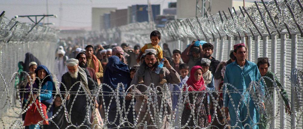Afghanen gehen an Zäunen entlang, als sie am 24. August 2021 nach der militärischen Übernahme Afghanistans durch die Taliban über den pakistanisch-afghanischen Grenzübergang in Chaman in Pakistan ankommen.