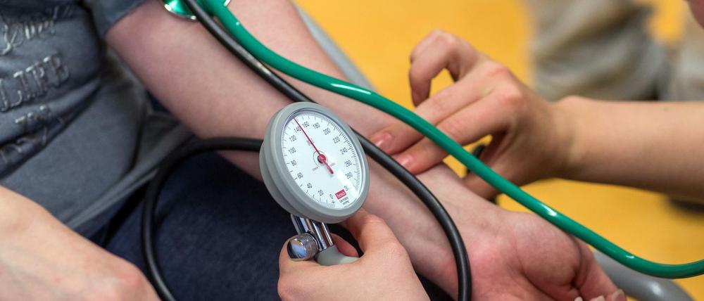 Auszubildene üben in einer Altenpflegeschule das Blutdruckmessen.