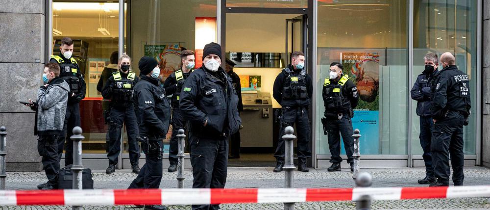 Polizisten stehen vor der Hypovereinsbank in der Friedrichstraße. Bankräuber haben die Bank überfallen und mehrere Menschen mit Reizgas verletzt.