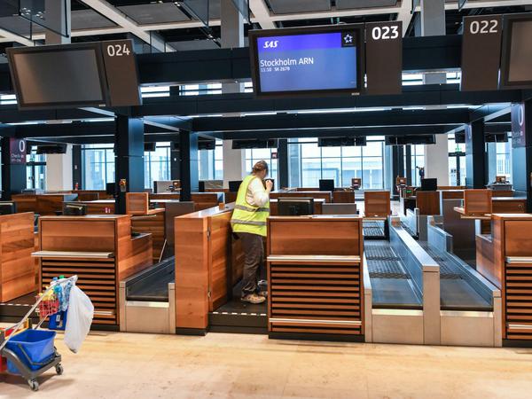Eine Angestellte einer Reinigungsfirma säubert einen Check-in-Schalter im Terminalgebäude des Hauptstadflughafens BER.