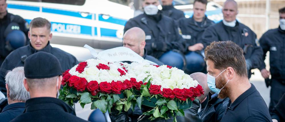Vorn ein Blumengebinde, hinten die Polizei: Eine Beerdigung im Kreise der Familie Remmo unter Corona-Bedingungen.