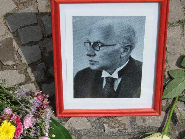 Blumen für Adolf Mockrauer. Vor den neuverlegten Stolperstein stellten die Bürger ein Porträt des Apothekers. 