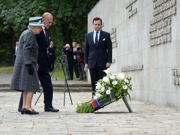 Die britische Königin Elizabeth II. und Prinz Philip legen an der Inschriftenwand einen Kranz nieder: "Zum Gedenken all derer, die an diesem Ort gestorben sind", steht da auf Englisch.