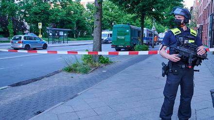 Ein schwer bewaffneter Polizist steht vor einer Absperrung in der Oranienstraße. Polizeiwagen stehen vor der Senatsverwaltung für Gesundheit. In dem Gebäude soll ein unbekannter Angreifer einen Bundeswehrsoldaten angegriffen haben.