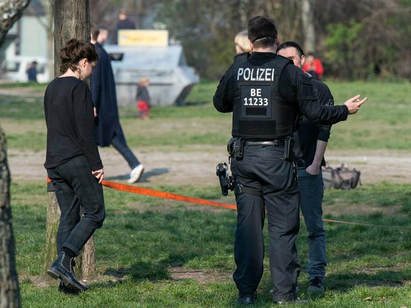 A police officer talking to a man in a public park in Berlin.