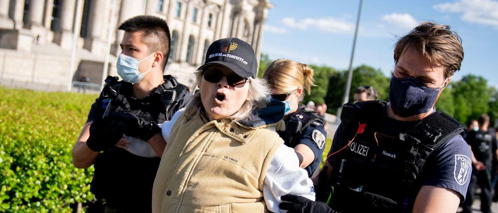 Eine Teilnehmerin von Corona-Protesten im März wird vor dem Reichstagsgebäude abgeführt.