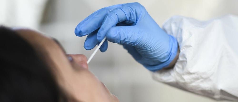 Eine Mitarbeiterin eines Testzentrums nimmt einen Nasenabstrich für einen Corona-Schnelltest.