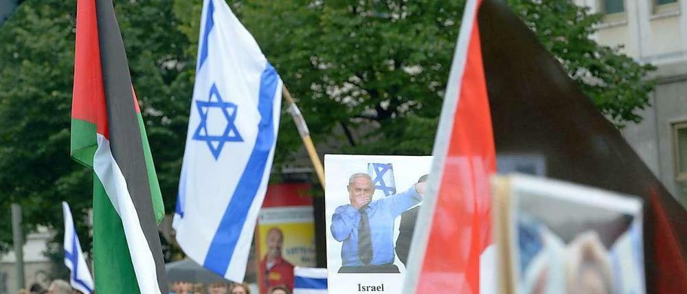 Israelische und palästinensische Fahne friedlich nebeneinander? Nein, bei diesem Foto von Demonstranten der verschiedenen Lager am sogenannten Al-Quds-Tag in Berlin täuscht die Perspektive. 