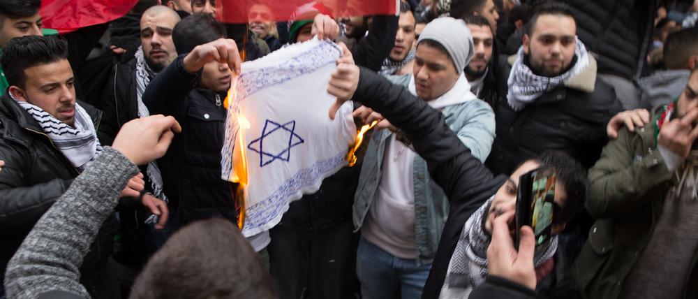 Teilnehmer einer Demonstration in Neukölln verbrennen eine selbstgemalte Fahne mit einem Davidstern. (Archivbild)